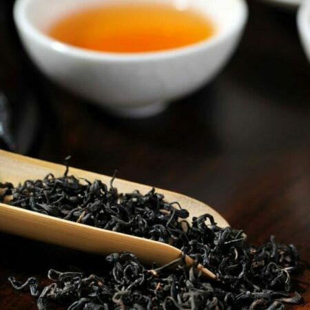 cuillère en bois de thé noir et bol de thé infusé